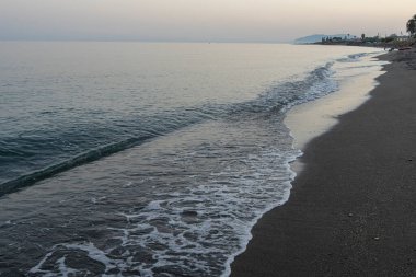 İspanya 'nın Malaga kentindeki sakin bir sahilde alacakaranlıkta hafif dalgalar kıyıya vurur. Rahatlama, kıyı dinginliği ve doğanın güzelliği için mükemmel bir tema..