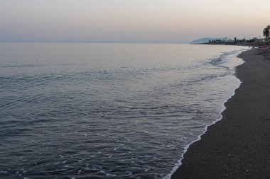 İspanya 'nın Malaga kentindeki sakin bir sahilde alacakaranlıkta hafif dalgalar kıyıya vurur. Rahatlama, kıyı dinginliği ve doğanın güzelliği için mükemmel bir tema..