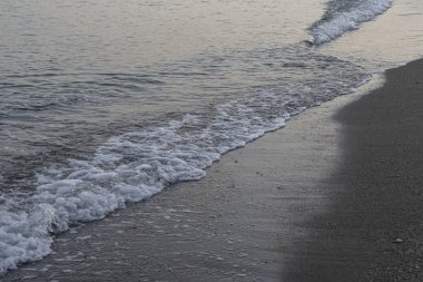 İspanya 'nın Malaga kentindeki sakin bir sahilde alacakaranlıkta hafif dalgalar kıyıya vurur. Rahatlama, kıyı dinginliği ve doğanın güzelliği için mükemmel bir tema..