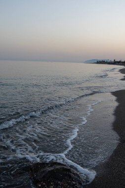 İspanya 'nın Malaga kentindeki sakin bir sahilde alacakaranlıkta hafif dalgalar kıyıya vurur. Rahatlama, kıyı dinginliği ve doğanın güzelliği için mükemmel bir tema..