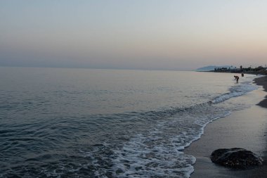 İspanya 'nın Malaga kentindeki sakin bir sahilde alacakaranlıkta hafif dalgalar kıyıya vurur. Rahatlama, kıyı dinginliği ve doğanın güzelliği için mükemmel bir tema..