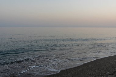 İspanya 'nın Malaga kentindeki sakin bir sahilde alacakaranlıkta hafif dalgalar kıyıya vurur. Rahatlama, kıyı dinginliği ve doğanın güzelliği için mükemmel bir tema..