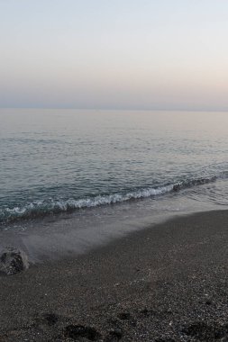 İspanya 'nın Malaga kentindeki sakin bir sahilde alacakaranlıkta hafif dalgalar kıyıya vurur. Rahatlama, kıyı dinginliği ve doğanın güzelliği için mükemmel bir tema..