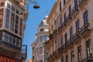 İspanya 'nın Malaga şehrinde, pencereleri ve saksıları kapalı geleneksel balkonların bulunduğu büyüleyici bir cephe. İspanyol mimarisini, kültürünü ve şehir estetiğini resmetmek için mükemmel.