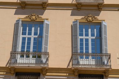 İspanya 'nın Malaga şehrinde, pencereleri ve saksıları kapalı geleneksel balkonların bulunduğu büyüleyici bir cephe. İspanyol mimarisini, kültürünü ve şehir estetiğini resmetmek için mükemmel.