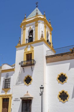 İspanya 'nın Ronda kentindeki Nuestra Senora de la Merced Kilisesi' nin göz kamaştırıcı cephesinde, parlak mavi gökyüzünün altında ikiz çan kuleleri ve merkezi bir çeşme bulunuyor. İspanyol mimarisi, dini simgeler ve kültür turizmi için mükemmel bir tema.