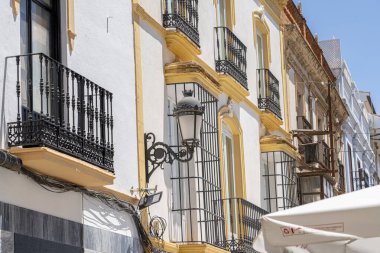 İspanya 'nın Ronda kentindeki tarihi bir kilise çan kulesinin yakından görüntüsü, açık mavi gökyüzüne karşı klasik sarı ve beyaz mimari detaylar içeriyor. Kültürel ve mimari temalar için ideal.