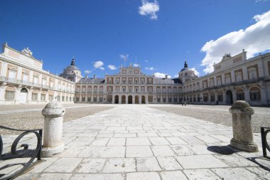Ziyaretçiler İspanya 'nın Aranjuez kentindeki Kraliyet Sarayı' nın etkileyici mimarisine hayran kaldılar. Avluda canlı mavi bir gökyüzünün arka planına karşı tarihi binalar yer alıyor..