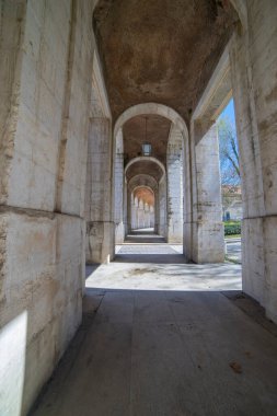 İspanya, Aranjuez 'deki sarayın güzel taş geçidini keşfedin. Bu tarihi mekan etkileyici kemerler ve 18. yüzyıldan kalma kraliyet mimarisini vurgulayan huzurlu bir atmosfere sahiptir..