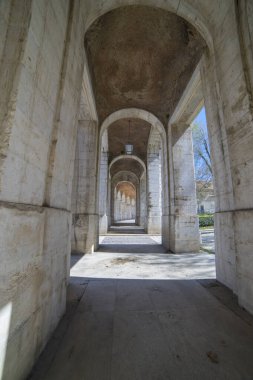 Ziyaretçiler, UNESCO 'nun Dünya Mirası bölgesi ve İspanya' daki eski kraliyet konutu olan Aranjuez Kraliyet Sarayı 'ndaki eski kemerlerle süslenmiş antik geçitte geziniyorlar..