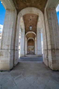 Ziyaretçiler, Aranjuez 'deki Kraliyet Sarayı' nın çarpıcı mimarisine hayran kalarak, tarihi kemerlerini ve parlak mavi gökyüzünün altında karmaşık ayrıntılarını gözler önüne seriyor..