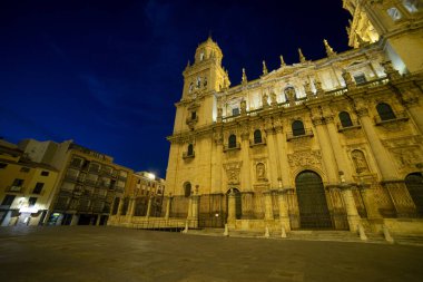 Katedral de Jaen zarif bir şekilde gece göğünün altında duruyor, karmaşık mimarisini ve aydınlatılmış detaylarını gözler önüne seriyor. Katedrali çevreleyen plaza çok sessiz..