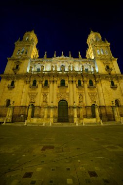 Katedral de Jaen 'in çarpıcı cephesi gece gökyüzüne karşı aydınlanmış, karmaşık mimari detaylar ve İspanya' nın Endülüs şehrinde ihtişam duygusu sergiliyor..