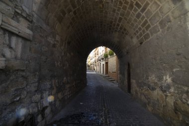 Antik bir taş kemer yolu Jaen, Endülüs 'te dar bir sokağı çerçeveler. Sessiz ve dingin olan bu pasaj bölgenin zengin tarihini ve mimarisini yansıtıyor..