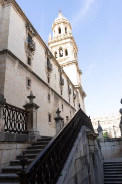 Ziyaretçiler, Jaen 'deki bu tarihi yere çıkan görkemli merdiveni tırmanırken Santa Iglesia Katedrali' nin çarpıcı mimarisine hayran kalıyorlar. Güneş, taş duvarlara uzun gölgeler bırakır..