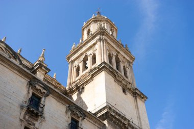 Ziyaretçiler, Jaen, Endülüs 'teki Santa Iglesia Katedrali' nin karmaşık tasarımına hayran kalarak, parlak mavi gökyüzüne karşı tarihi önemini ve güzel mimarisini sergiliyor..