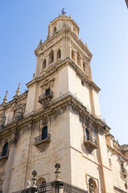 Santa Iglesia Katedrali 'nin etkileyici çan kulesi Jaen, Endülüs' teki açık mavi gökyüzüne karşı görkemli bir şekilde yükseliyor. Turistler bunun karmaşık mimari ayrıntılarına ve tarihsel önemine hayranlar..