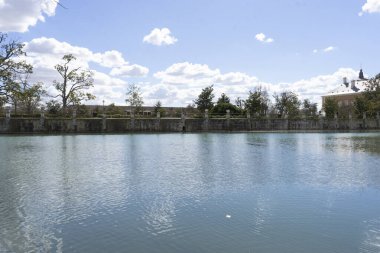 Ziyaretçiler, İspanya 'nın Aranjuez kentindeki Kraliyet Sarayı' nın bahçelerinin yakınlarındaki sakin sularda, yemyeşil ve tüylü bulutlarla bezenmiş mavi gökyüzüyle huzurlu bir öğleden sonranın tadını çıkarıyorlar..