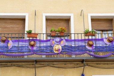 Canlı dekorasyonlar Brihuega 'da bir balkon süslüyor, hasır şapkalar ve mor kurdeleler sergileniyor, Guadalajara' da ilkbaharda düzenlenen geleneksel bir yerel festivali kutluyorlar..