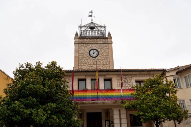 Brihuega 'daki Ayuntamiento binası, yerel şenlikler sırasında gurur ve kapsayıcılığı simgeleyen canlı bir gökkuşağı bayrağıyla süslenmiş tarihi mimarisini sergiliyor..