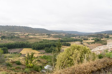 Brihuega, Guadalajara 'nın yuvarlanan tepelerini ve yemyeşil vadilerini bulutlu bir günde gösteren güzel bir manzara. Yeşillik ve tarım alanları kırsal alanda resim gibi bir ortam yaratıyor..