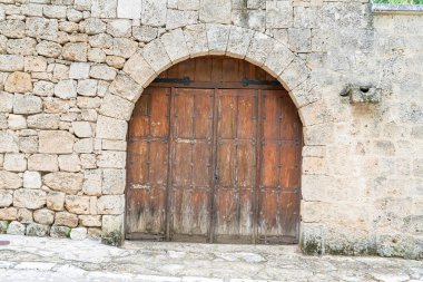 İspanya 'nın Brihuega kentindeki taştan bir kemerin içindeki aşınmış ahşap kapı Castilla-La Mancha' nın tarihi mimarisini gözler önüne seriyor. Kaba ayrıntılar bölgenin zengin kültür mirasını vurguluyor.