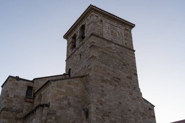 Castilla y Leon 'daki Zamora' da akşam gökyüzüne uzanan çarpıcı taş bir kilise kulesi. Yapıda karmaşık ayrıntılar yer alıyor ve bölgenin zengin tarihinin bir kanıtı olarak duruyor..