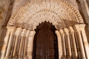 Ziyaretçiler, İspanya, Castilla y Leon 'da Zamora' da ahşap kapılara açılan süslü kemerli bir kemerin ayrıntılı taş işçiliğine hayran kaldılar. Bu tarihi mekan olağanüstü bir işçilik sergiliyor..