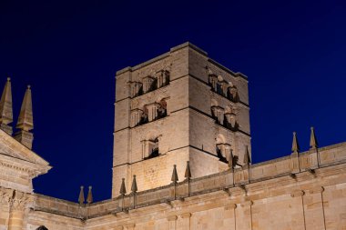 Derin mavi gökyüzünün altında, tarihi bir çan kulesi belirgin bir şekilde Zamora, Castilla y Leon 'da duruyor. Mimarinin karmaşık ayrıntıları ortaçağ döneminin işçiliğini vurguluyor..