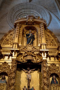 Ziyaretçiler, Colegiata de Santa Maria la Mayor de Toro 'daki altın yaprak ve dini heykellerle süslenmiş karmaşık sunağa hayran kalarak tarihi ve sanatsal önemini gözler önüne seriyor..