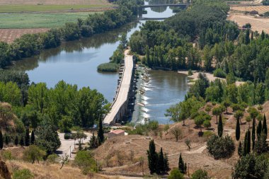 Toro, Zamora 'dan geçen Douro Nehri manzarası, yemyeşil ve eşsiz bir köprü. Huzurlu ortam bölgenin doğal güzelliğini ve kırsal çekiciliğini vurguluyor.