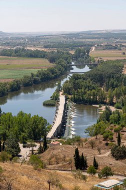 Toro, Zamora 'daki nehre bakan bu büyüleyici manzara, açık bir gökyüzünün altındaki yeşil ve tepelerle çevrili, bankaları birbirine bağlayan mühendislik köprüsünü vurguluyor..