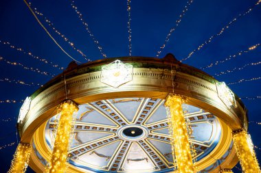 Aydınlatılmış sütunlar ve dekoratif tasarımlar, ziyaretçilerin akşam etkinlikleri ve ışıklardan hoşlandıkları Pamplona, Navarra, İspanya 'daki Plaza del Castillo' da şenlikli bir ortam yaratıyor..