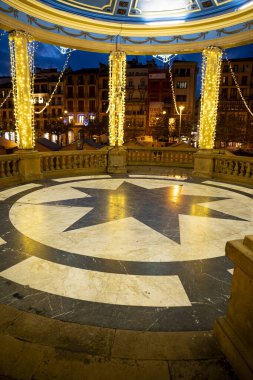 Akşam Plaza del Castillo 'da sıcak ışıklar parıldıyor, ziyaretçiler Pamplona' nın canlı yerinin tadını çıkarırken güzel mimarisini ve davetkar atmosferini sergiliyor..