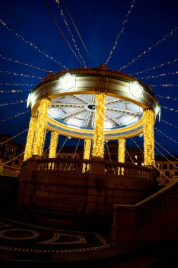 Ziyaretçiler, İspanya 'nın Pamplona kentindeki Plaza del Castillo' da keyifli bir akşamın tadını çıkarıyorlar. Güzel dekore edilmiş orkestra sehpası parlak ışıklarla aydınlatılıyor ve herkes için şenlikli bir ortam yaratıyor..