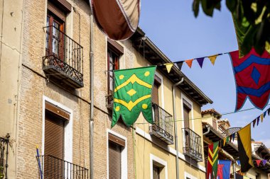 Alcala de Henares 'teki Ortaçağ Fuarı sırasında, binaların arasında canlı bayraklar ve pankartlar asılıydı ve ziyaretçiler Madrid' de geleneksel şenliklerin keyfini çıkarırken, turistik atmosfere canlılık katıyordu..