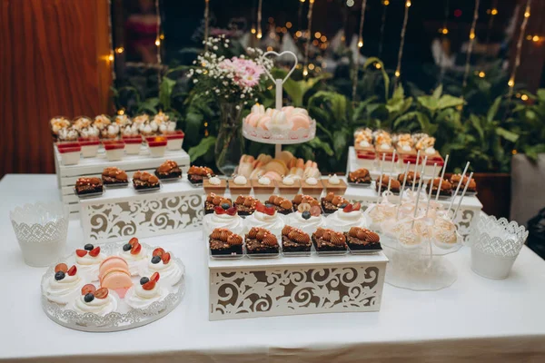 luxury wedding catering, table with modern desserts, cupcakes, sweets with fruits. delicious candy bar at expensive wedding reception. space for text. shower. holiday celebration. High quality photo