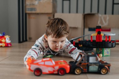 Çocuk oyuncak arabalarla oynuyor. Çocuk yerde oynuyor. Çocukların gündüz eğlencesi. Evde olduğum için mutluyum. Yüksek kalite fotoğraf