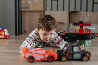 Çocuk oyuncak arabalarla oynuyor. Çocuk yerde oynuyor. Childs gündüz eğlencesi. Evde olduğum için mutluyum. Yüksek kalite fotoğraf