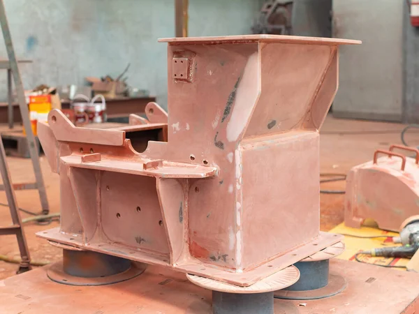 Hammer mill with a first layer of prime coating at industrial paint shop.