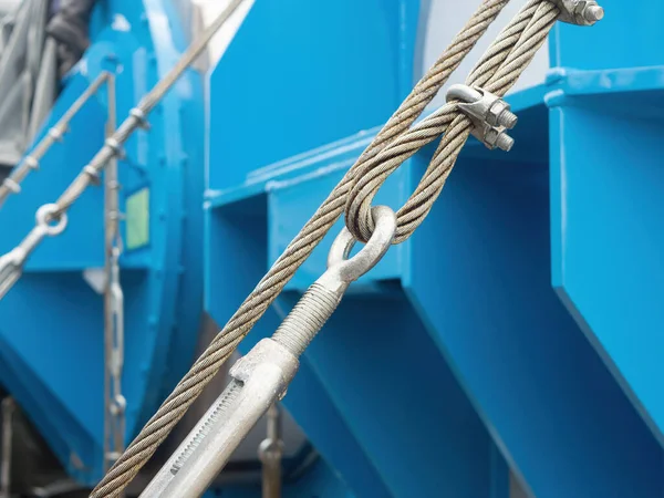 Wire rope with turnbuckles and clamps holding heavy machinery in place for shipment. Shallow depth of field with the foreground wire in focus.