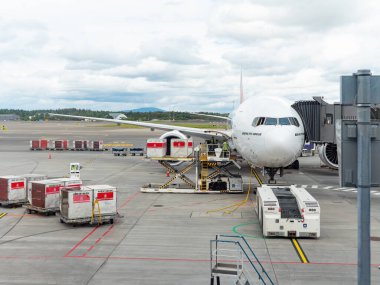 Gardermoen, Norveç - 22 Ağustos 2022: Emirates Boeing 777-300ER, Oslo Havaalanı, Gardermoen 'in kapısında, kalkıştan önce kargo ve bagaj konteynerleriyle yükleniyor..