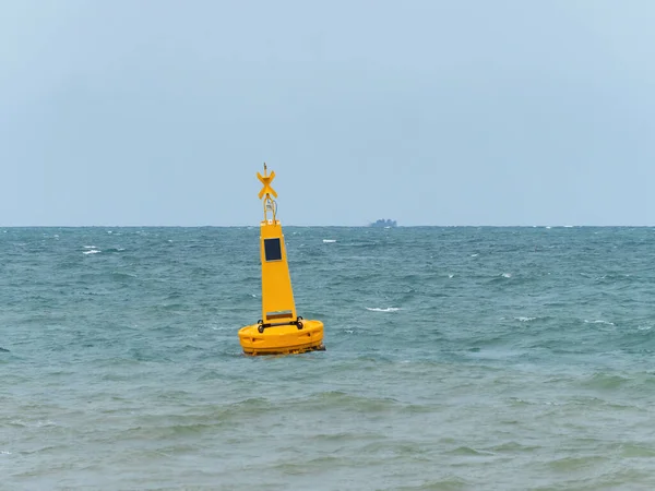 Yellow buoy with a solar powered light at sea to mark a danger area, in this case an area reserved for swimmers near a beach in Pattaya, Thailand.