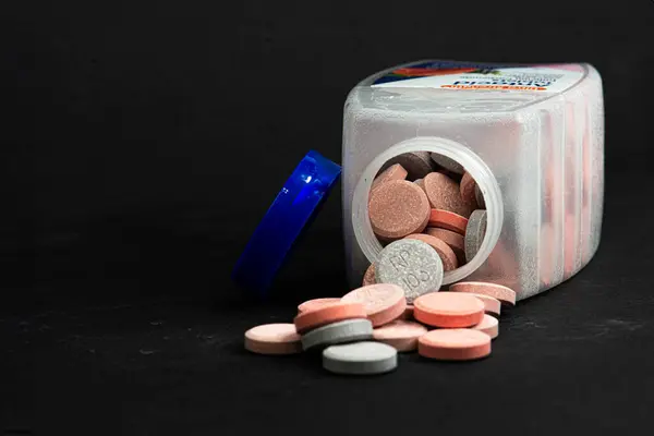Açılmış bir şişe Antacid döküldü. Yüzeyde bazı haplar var..
