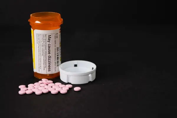 Pembe haplar şeklinde bir ilaç (RX). Hapların bir kısmı şişenin dışında..