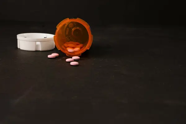 Pembe haplar şeklinde bir ilaç (RX). Bazı haplar şişenin dışına dökülmüş..