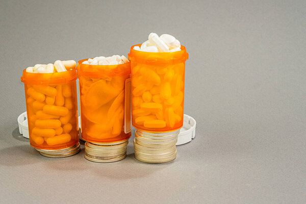 Три чересчур полные стопки рецептурных бутылок на лестнице серебряных долларов. Расходы - это концепция.