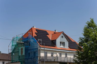 Güney Almanya 'da güneşli bahar gününde inşaat iskelesi olan çatıdaki güneş paneli.