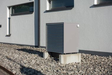 Yazın güneşli bir günde, güney Almanya 'nın modern ev cepheleriyle yeni bir binada sıcak hava pompası.