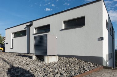 Yazın güneşli bir günde, güney Almanya 'nın modern ev cepheleriyle yeni bir binada sıcak hava pompası.